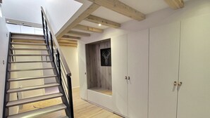 A modern interior with a wooden staircase, built-in wardrobe, and a small alcove with a decorative wall piece. - Charming 3-bedroom house in the vineyard with terrace (Vœgtlinshoffen)