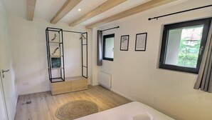 A bedroom with a bed, a hanging shelf, a window with curtains, and a radiator. - Charming 3-bedroom house in the vineyard with terrace (Vœgtlinshoffen)