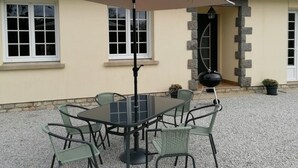 A patio with a table and chairs, an umbrella, and a barbecue grill. - Single-story house with garden and parking in Yvetot-Bocage (Yvetot-Bocage)
