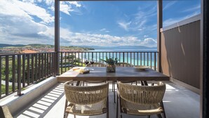 Un balcon avec une table et des chaises, offrant une vue sur la côte.