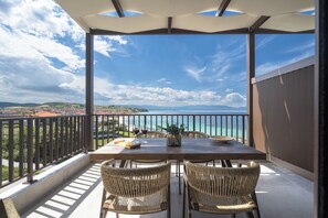 A balcony with a table and chairs, overlooking a coastal view. - Blue Whisper Luxury Living Suites (Aristotelis)