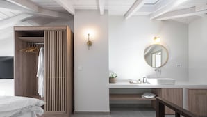 Een moderne slaapkamer met een houten garderobe, een nachtkastje, een ronde spiegel en een witte wasbak.