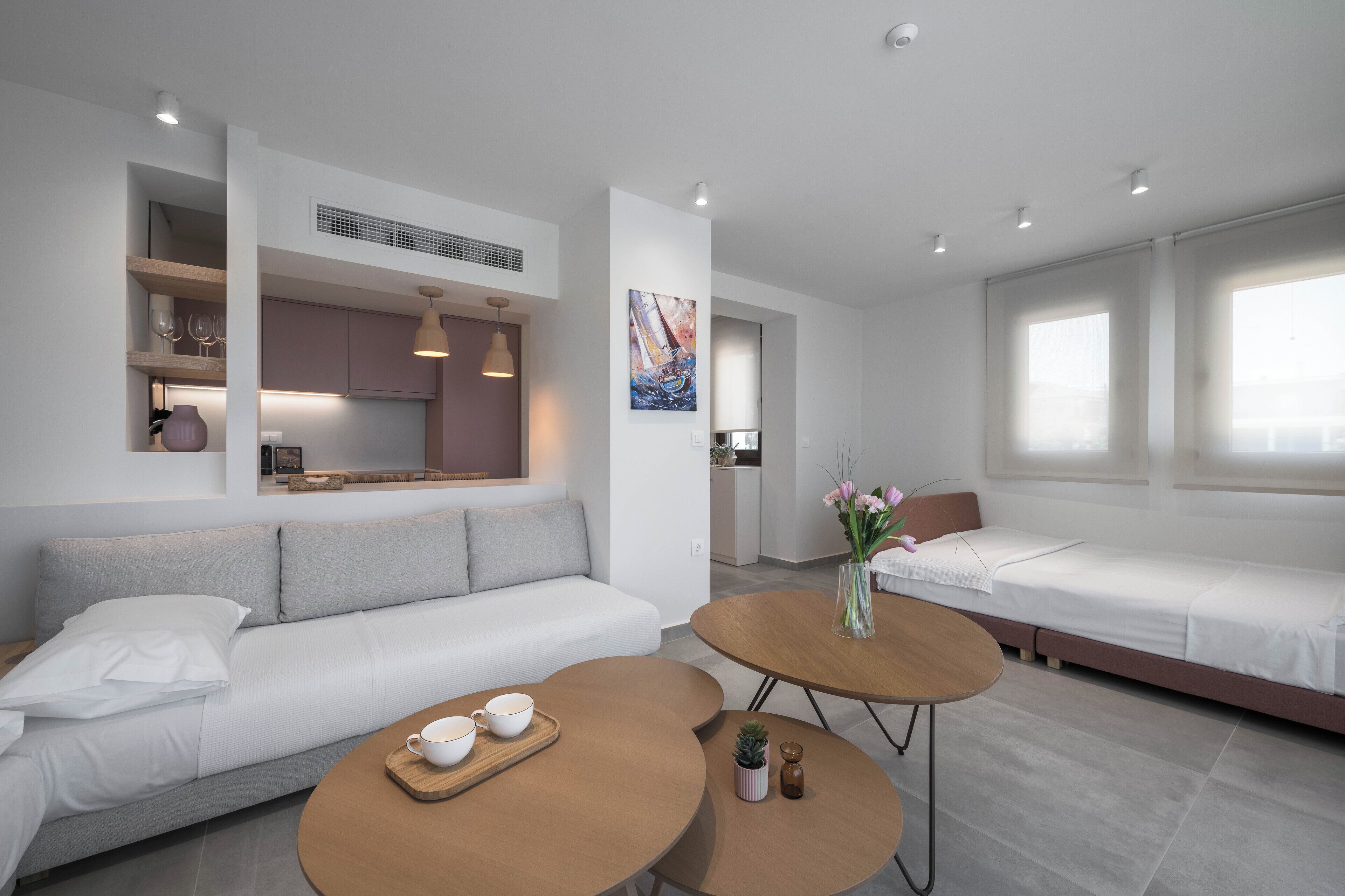 Una habitación de hotel moderna con sofá, una pequeña mesa de comedor, una cama y una kitchenette.