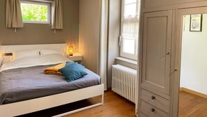 Ein Schlafzimmer mit Bett, Nachttisch, Heizkörper und Kleiderschrank.