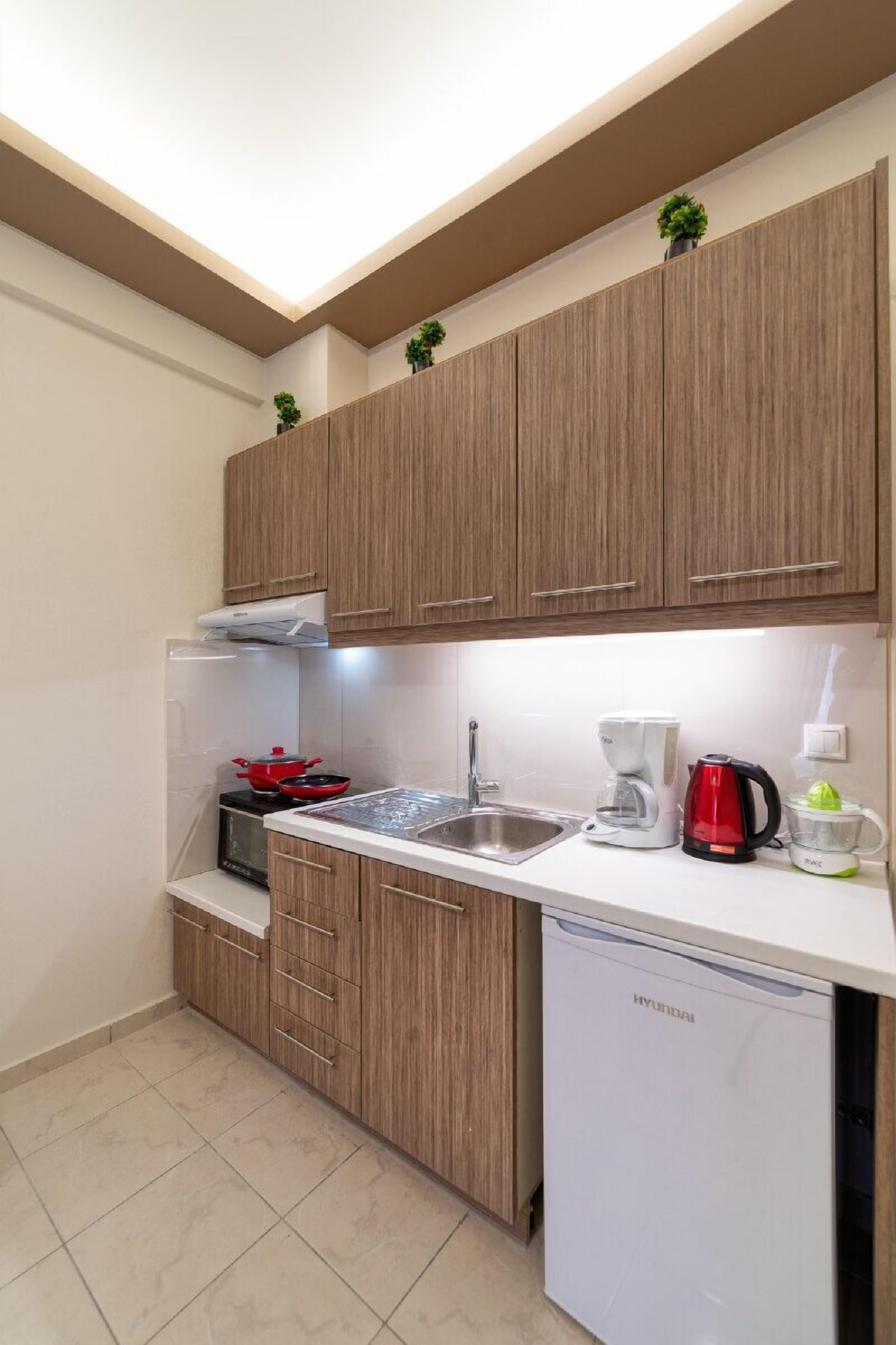 A compact kitchen with wooden cabinets, a built-in microwave, a sink, and a dishwasher.