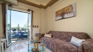 Ein Wohnzimmer mit einem Glastisch, einem braunen, gemusterten Sofa und einem Bild an der Wand.