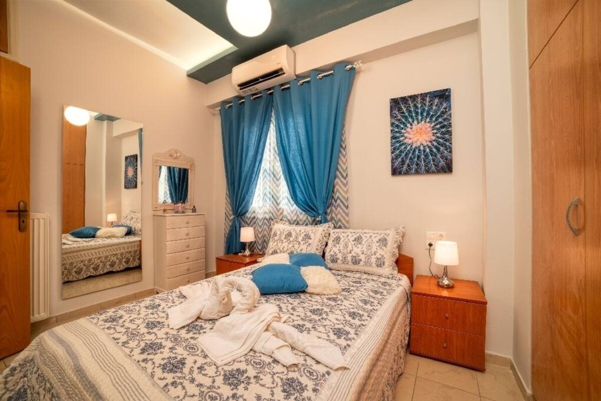 Een slaapkamer met een bed, nachtkastjes, een dressoir, een spiegel en een plafondventilator.