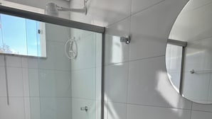 Een moderne badkamer met een douchecabine van glas, een toilet, een wastafel en een spiegel.