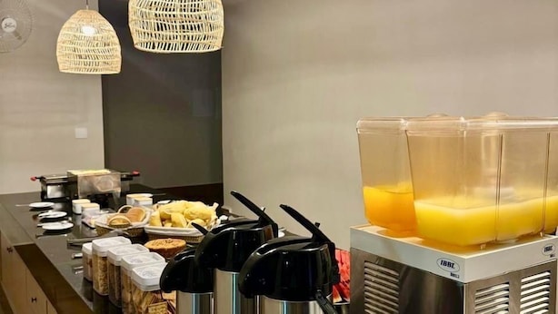 Een ontbijtbuffet met diverse etenswaren, waterkokers en een sapdispenser.