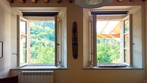 A bedroom with two windows, a radiator, a bed, and a wooden ceiling.