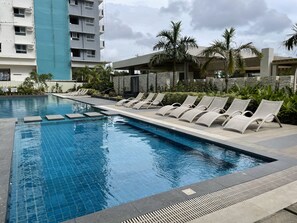 A swimming pool with lounge chairs and palm trees.