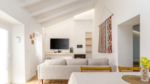 A modern living room with a sofa, a dining table, and a TV. - Cottage in Aljezur- 2 bed Ensuite-casinha da Ivone (Aljezur)