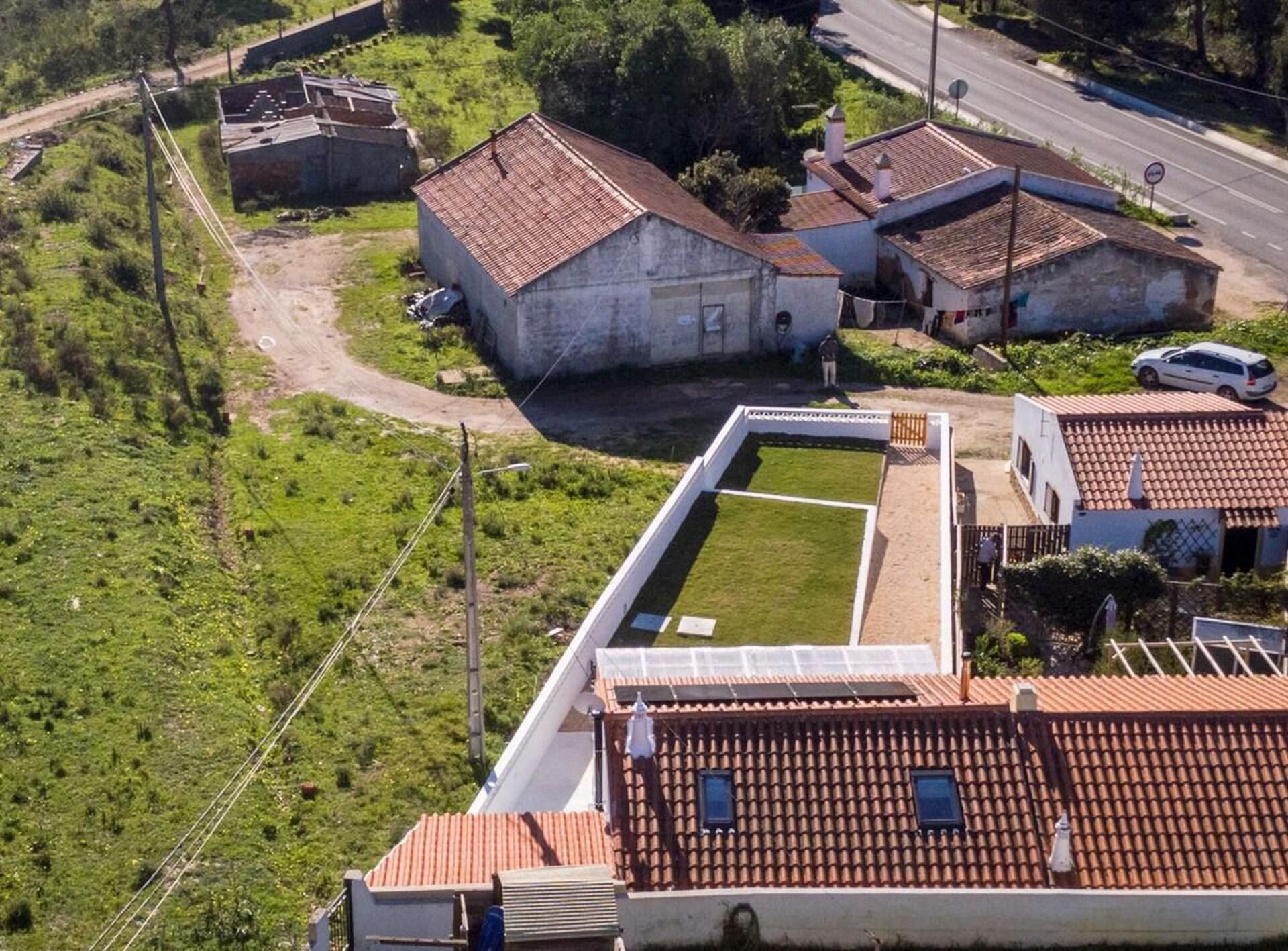 Vista aérea de una zona residencial con casas, una carretera y un campo cubierto de césped.