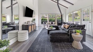 A modern living room with a fireplace, comfortable seating, and large windows offering a view of the outdoors. - Golf View Home with Fire Pit & BBQ (Flagstaff)