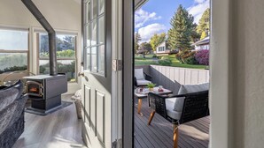 A deck with a wood-burning stove, outdoor seating, and a view of a garden and neighboring houses. - Golf View Home with Fire Pit & BBQ (Flagstaff)