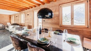 Interno in legno con tavolo da pranzo per sei persone, ampie finestre e vista sulle montagne.