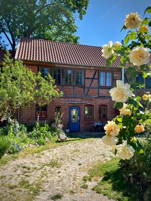 Traditional home with a brick exterior, surrounded by a beautiful garden and a clear path to the entrance.