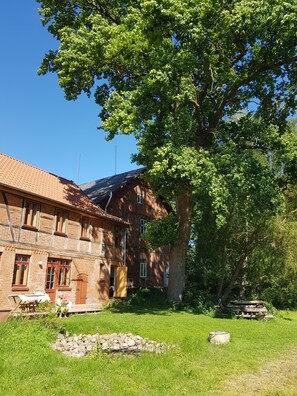 A traditional brick building with a tiled roof, surrounded by a well-maintained lawn and a large tree. - Wunderschönes Gästehaus (Neritz)