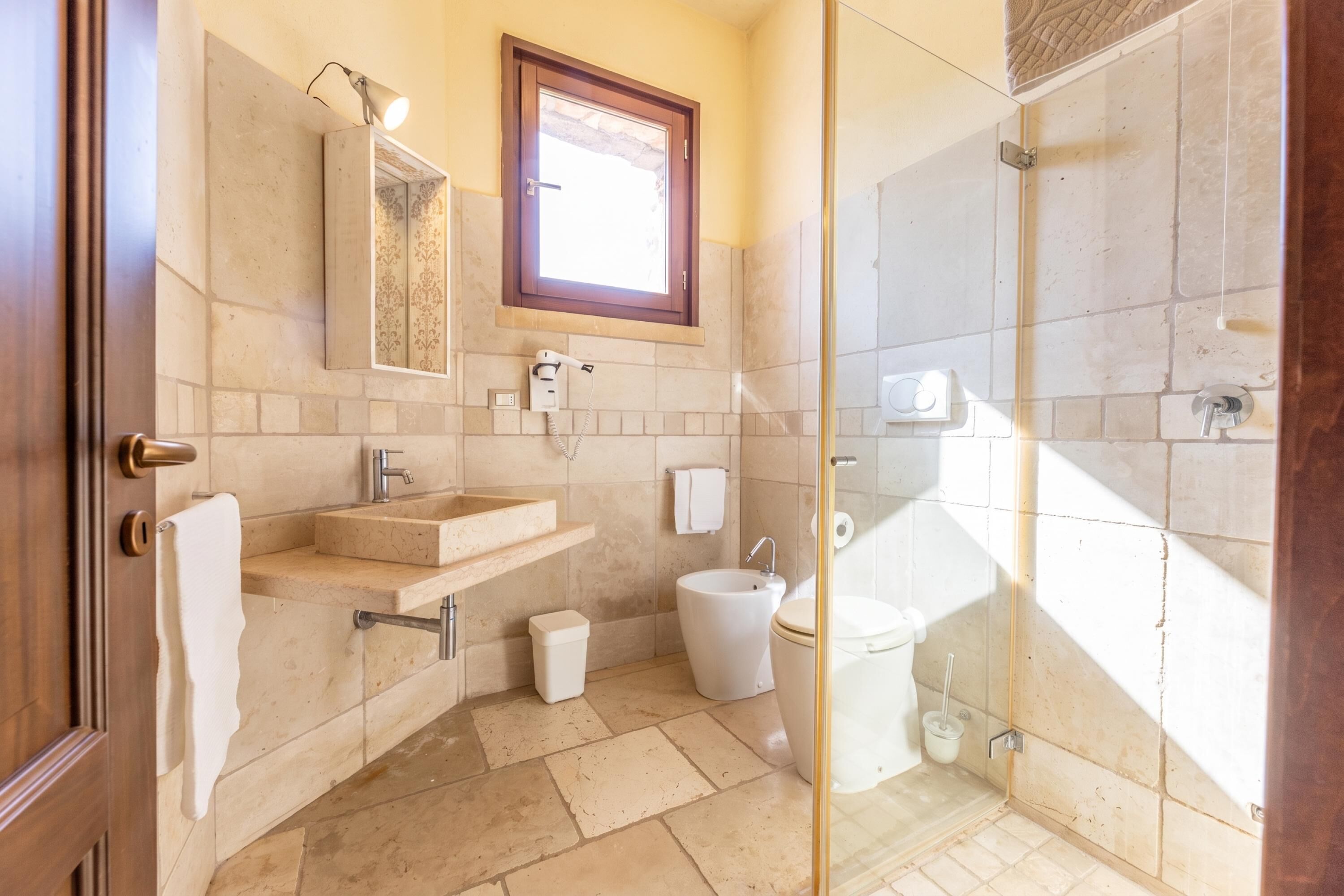 Une salle de bain avec une douche à parois de verre, un lavabo avec un miroir, des toilettes et un porte-serviettes.