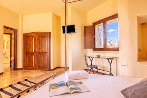 Een hotelkamer met een bed, een zithoek met een tijdschrift, een raam met uitzicht en een houten deur.