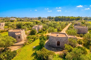 A rural setting with stone buildings surrounded by greenery and a clear sky. - Villetta Il Morige (Galatone)