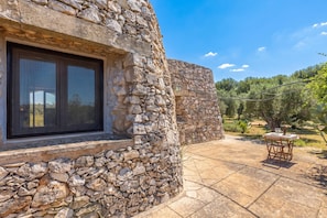 A stone building with a window and a patio area with a table and chairs. - Villetta Il Morige (Galatone)