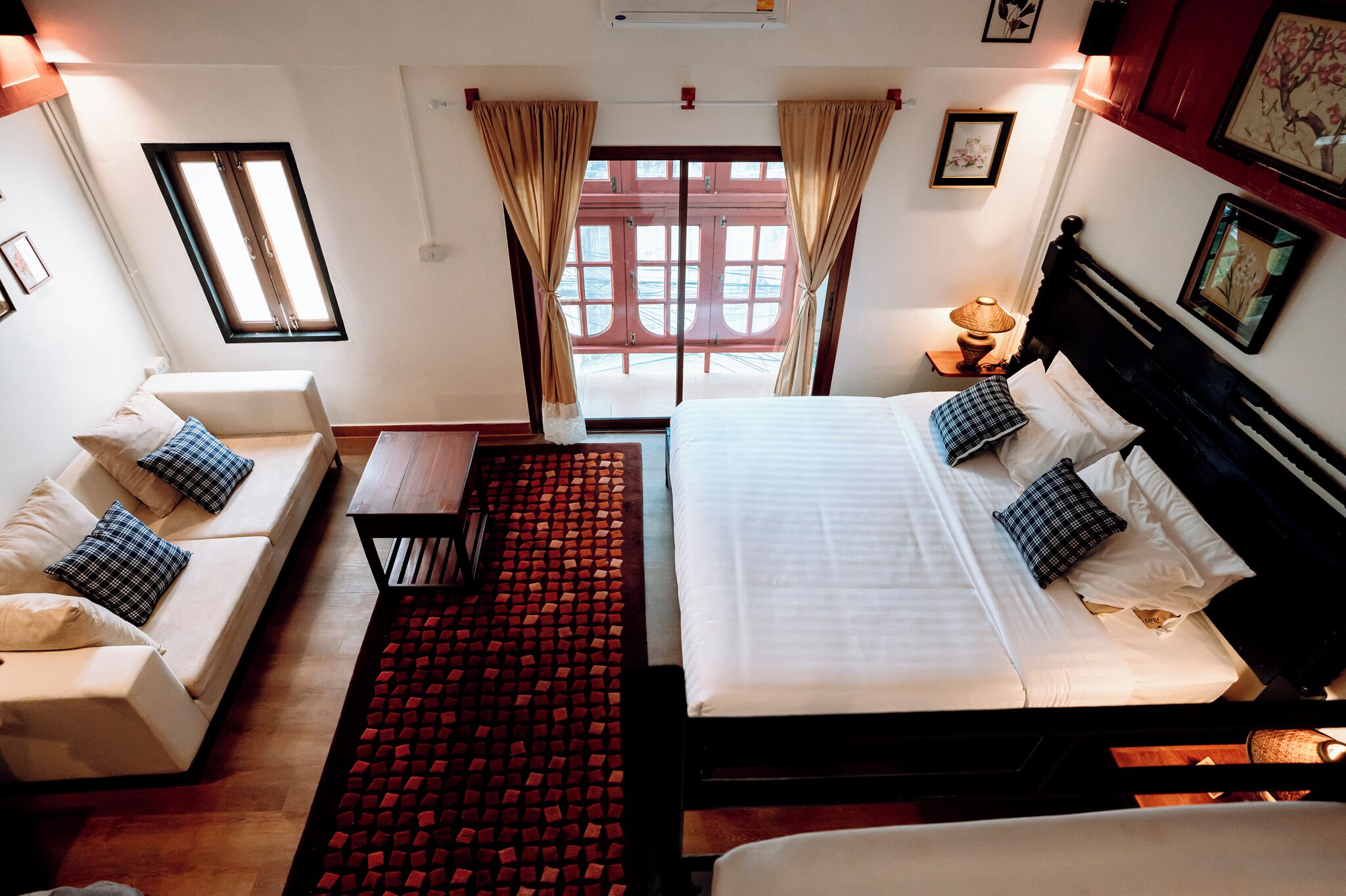 Una habitación de hotel con cama, sofá, una mesita y alfombra roja.