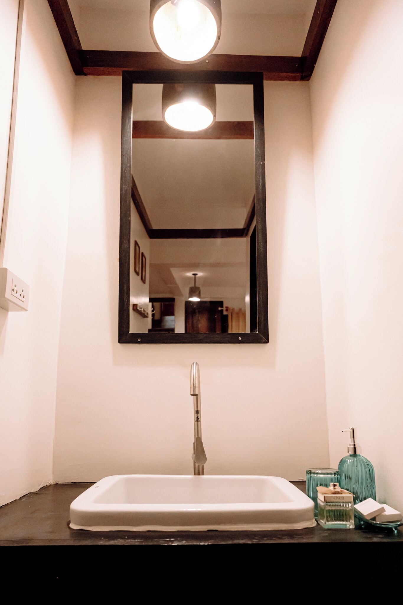 A bathroom with a white sink, a mirror, and a light fixture above it.