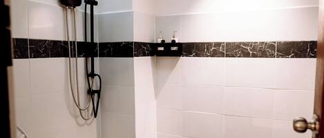 Un baño con ducha, inodoro y azulejos de mármol.