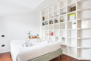 Relax in a serene space with a large bed, bedside table, and shelving unit, perfect for unwinding.