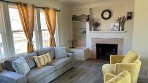 A living room with a grey sofa, yellow armchair, fireplace, and a clock on the wall. - A newly renovated home full of fun games for the entire family to enjoy. (Thermopolis)