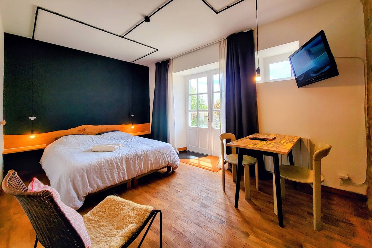 Ein Schlafzimmer mit einem Bett, einem Schreibtisch, einem Stuhl, einem Fernseher und einem Fenster.