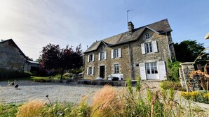 Une maison en pierre avec un toit en pente, de nombreuses fenêtres et une cheminée.