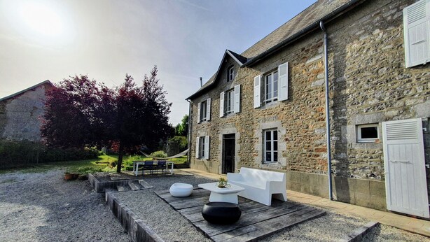 Un bâtiment en pierre doté d’une terrasse en gravier, d’un espace extérieur aménagé pour s’asseoir et d’un petit jardin.