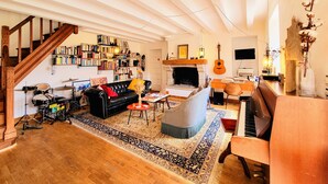 Un salon spacieux avec une cheminée, des étagères à livres, une batterie et une guitare.