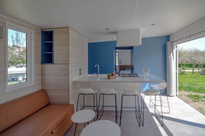 Una cocina moderna con una isla central, taburetes de bar y un banco empotrado.