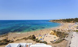 A beach with clear blue waters, sandy shores, and a few boats.