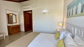 A bedroom with a bed, bedside table, lamp, and a painting on the wall.