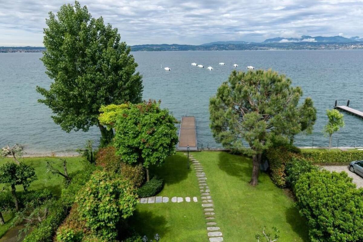 Un jardin au bord du lac, avec un sentier en pierre menant à un quai.