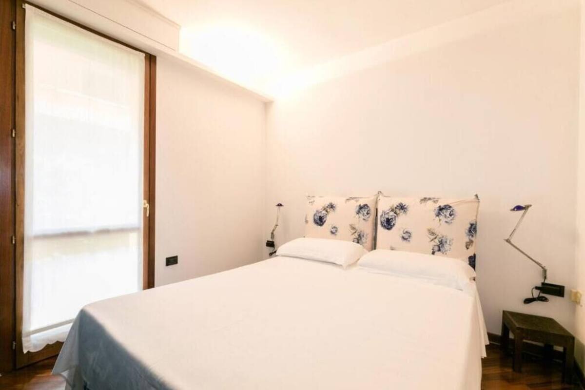 Une chambre à coucher avec un lit, des lampes de chevet, une petite table et une porte coulissante.