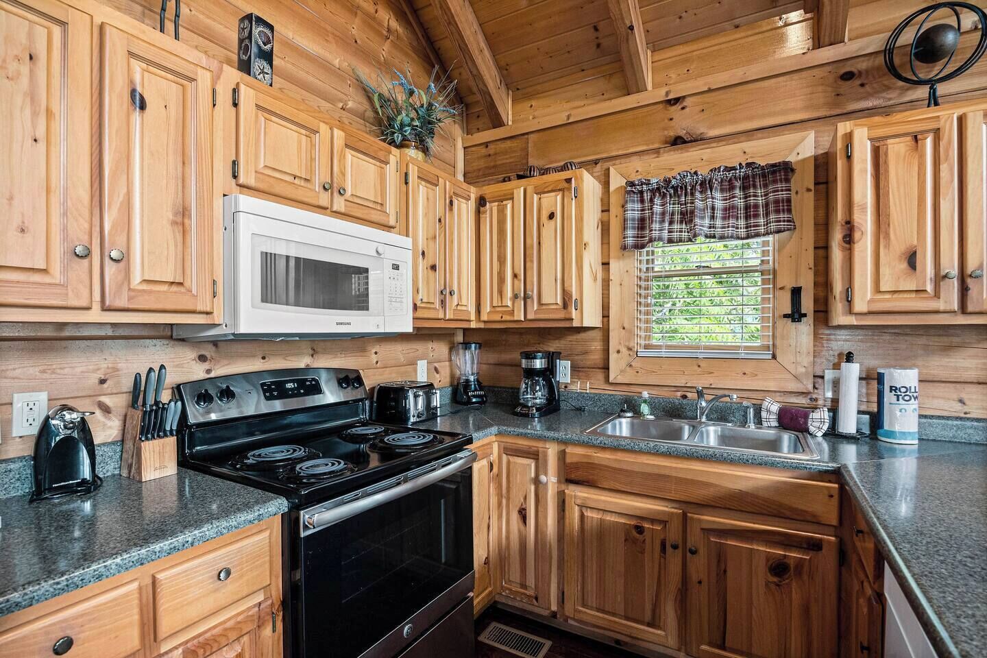 A kitchen with wooden cabinets, a microwave, a stove, and a sink.