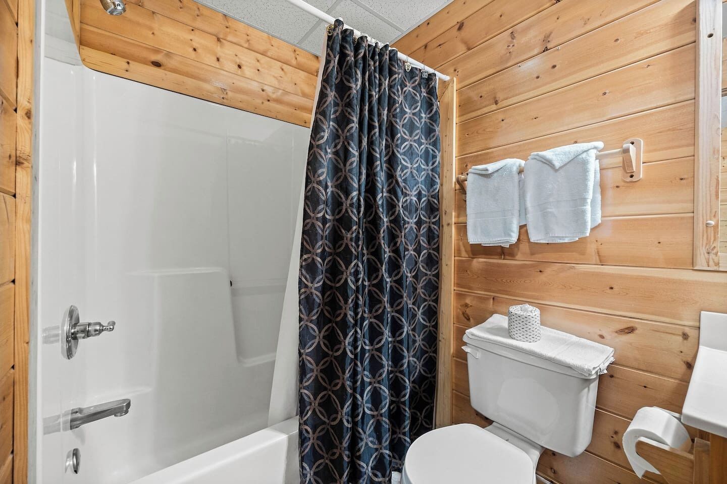 Un baño con ducha, inodoro y lavamanos, todo con accesorios blancos.