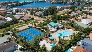 Et boligområde med en stor swimmingpool, tennisbaner og udsigt til havet.