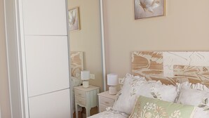 A bedroom with a bed, a nightstand, a mirror, and a wall-mounted painting. - El Capricho Suite La Terraza con Parking Incluido (Gijón)