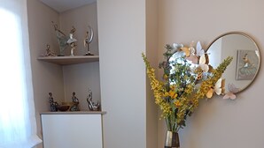 A living room with a green sofa, a small round table, a white cabinet with leaf patterns, and a vase with flowers. - El Capricho Suite La Terraza con Parking Incluido (Gijón)