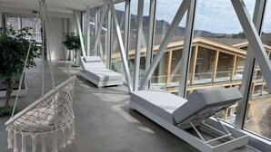 Ein modernes Interieur mit großen Fenstern, einer Hängematte und zwei Loungesesseln.