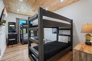 A bunk bed room with a desk and a lamp.