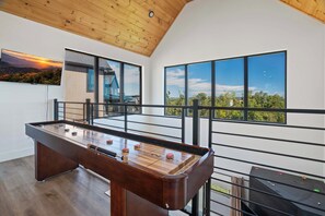 A pool table in a room with large windows, wooden ceiling, and a view of a house and trees. - Heated Indoor Pool, Luxury Cabin, Near Dollywood (Sevierville)
