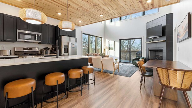 A modern kitchen with a central island, bar stools, and a dining area with a table and chairs.