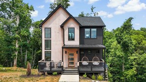 A two-story cabin with a deck, large windows, and a dark roof.
